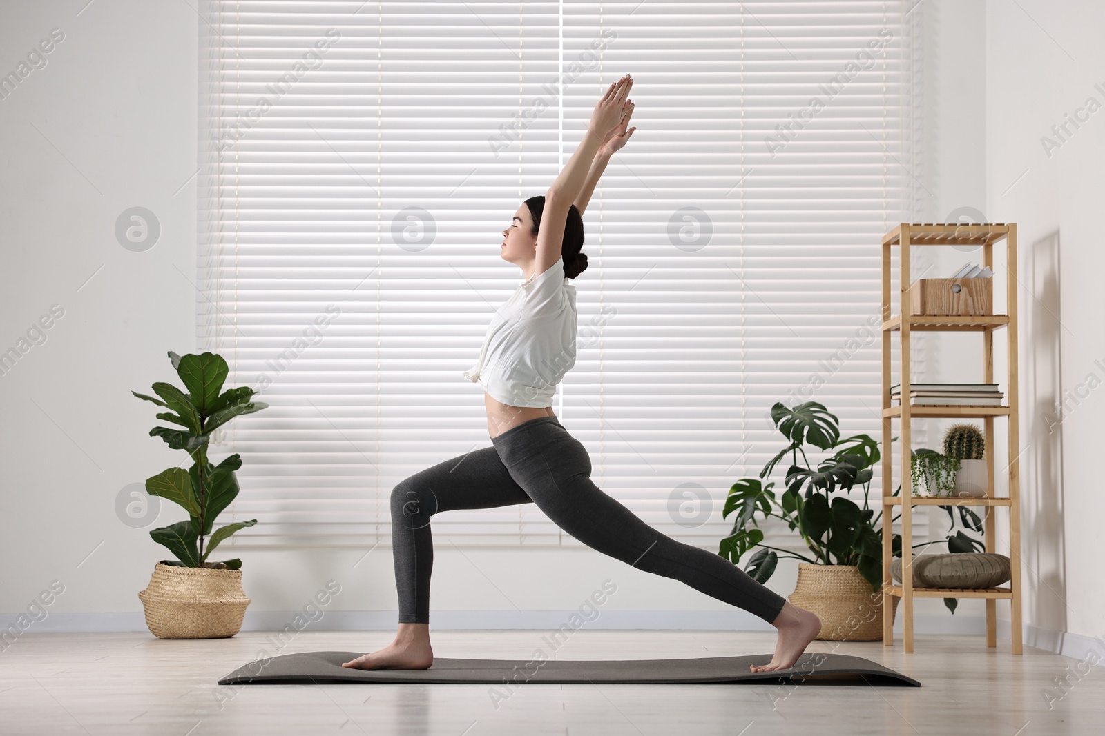 Photo of Girl practicing crescent asana on mat in yoga studio. High lunge pose