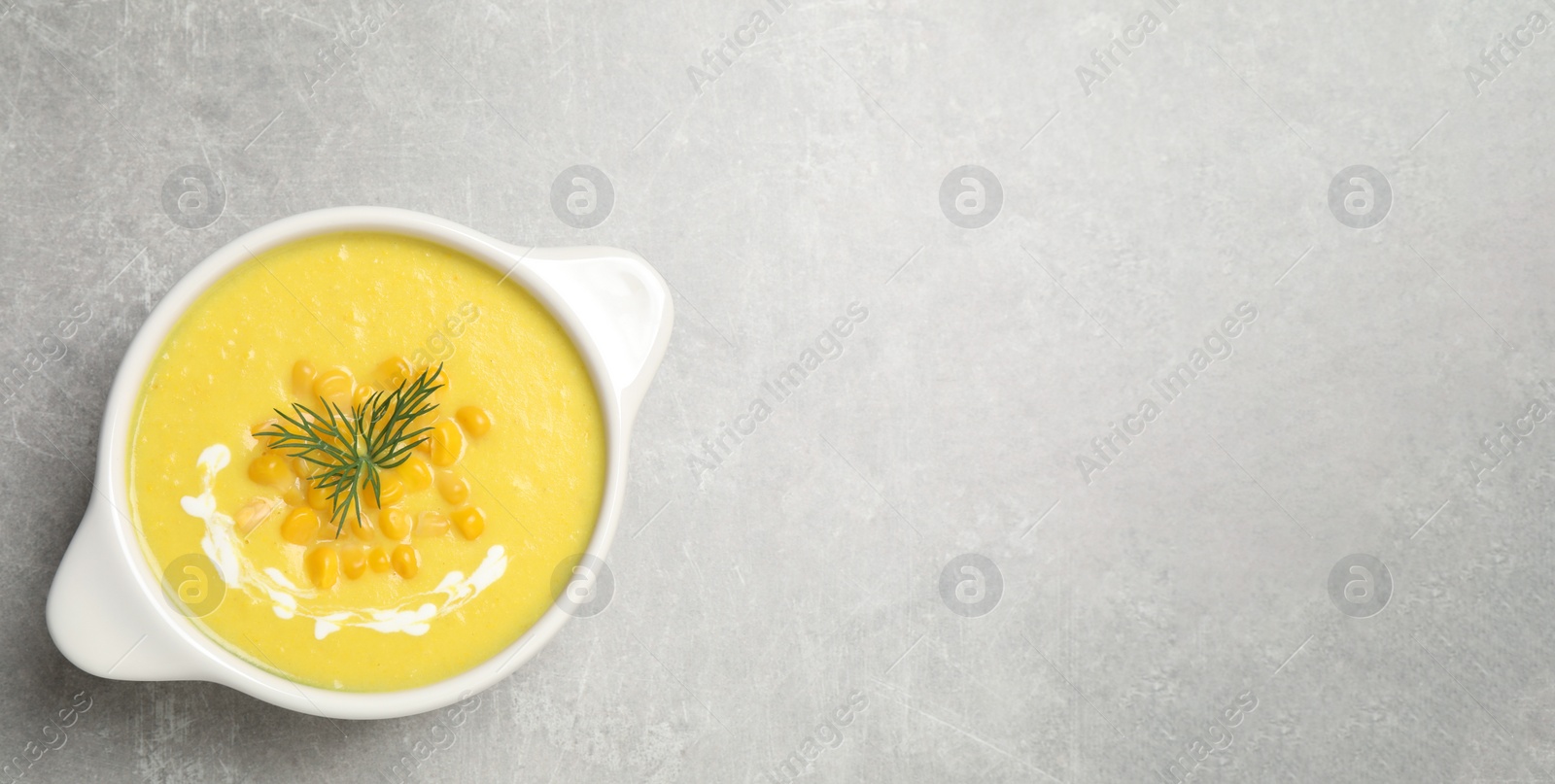 Photo of Delicious creamy corn soup on grey table, top view. Space for text