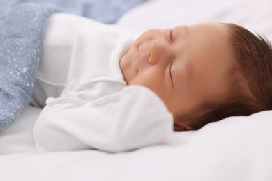 Photo of Cute newborn baby sleeping under blue blanket on bed, closeup