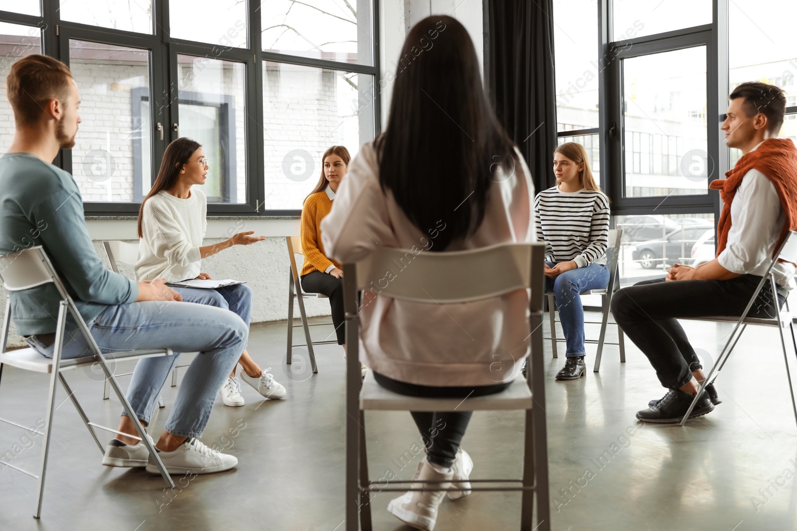 Photo of Psychotherapist working with patients in group therapy session indoors