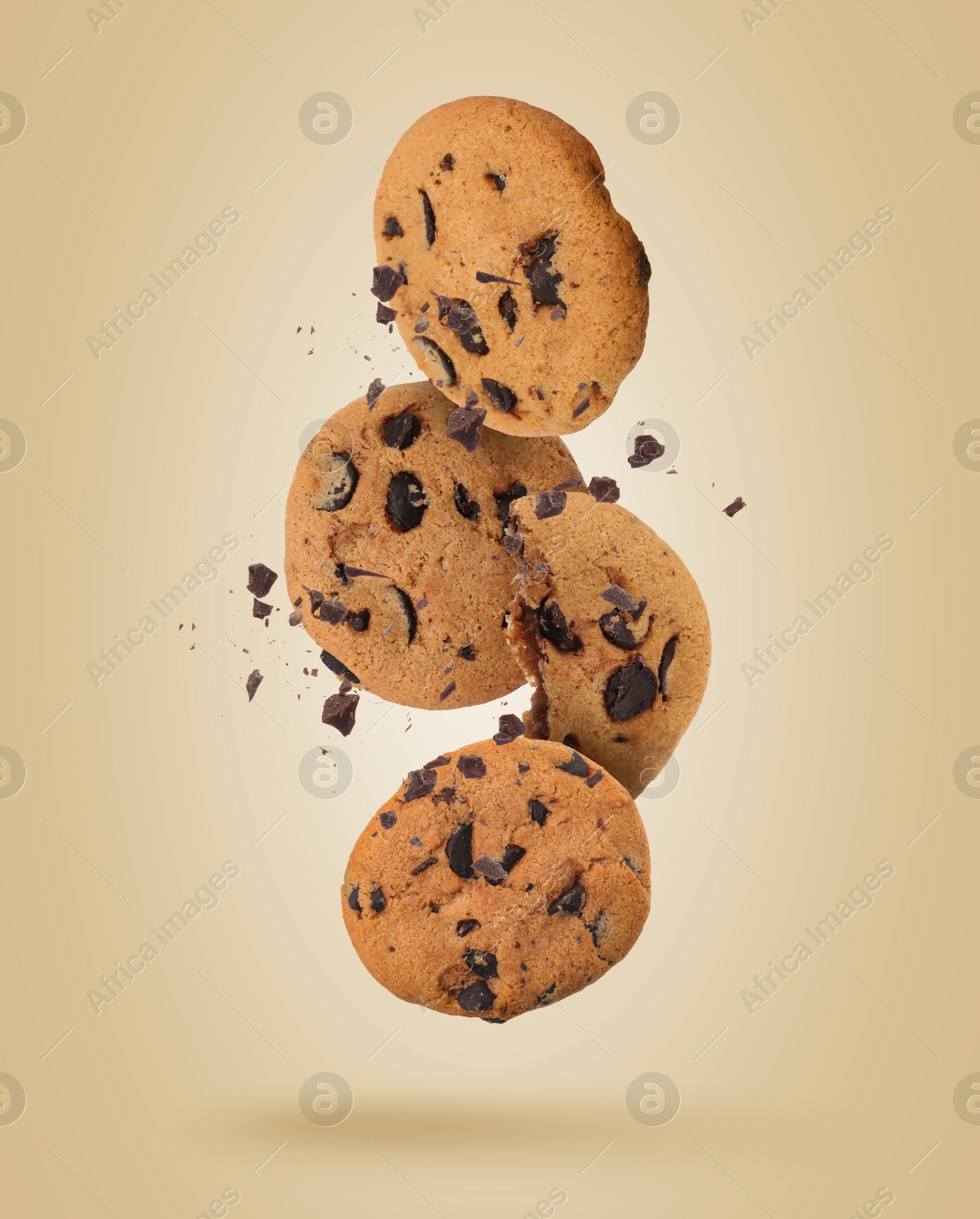 Image of Tasty chocolate chip cookies falling on pale light brown background