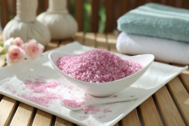 Photo of Bowl of pink sea salt on wooden table, closeup