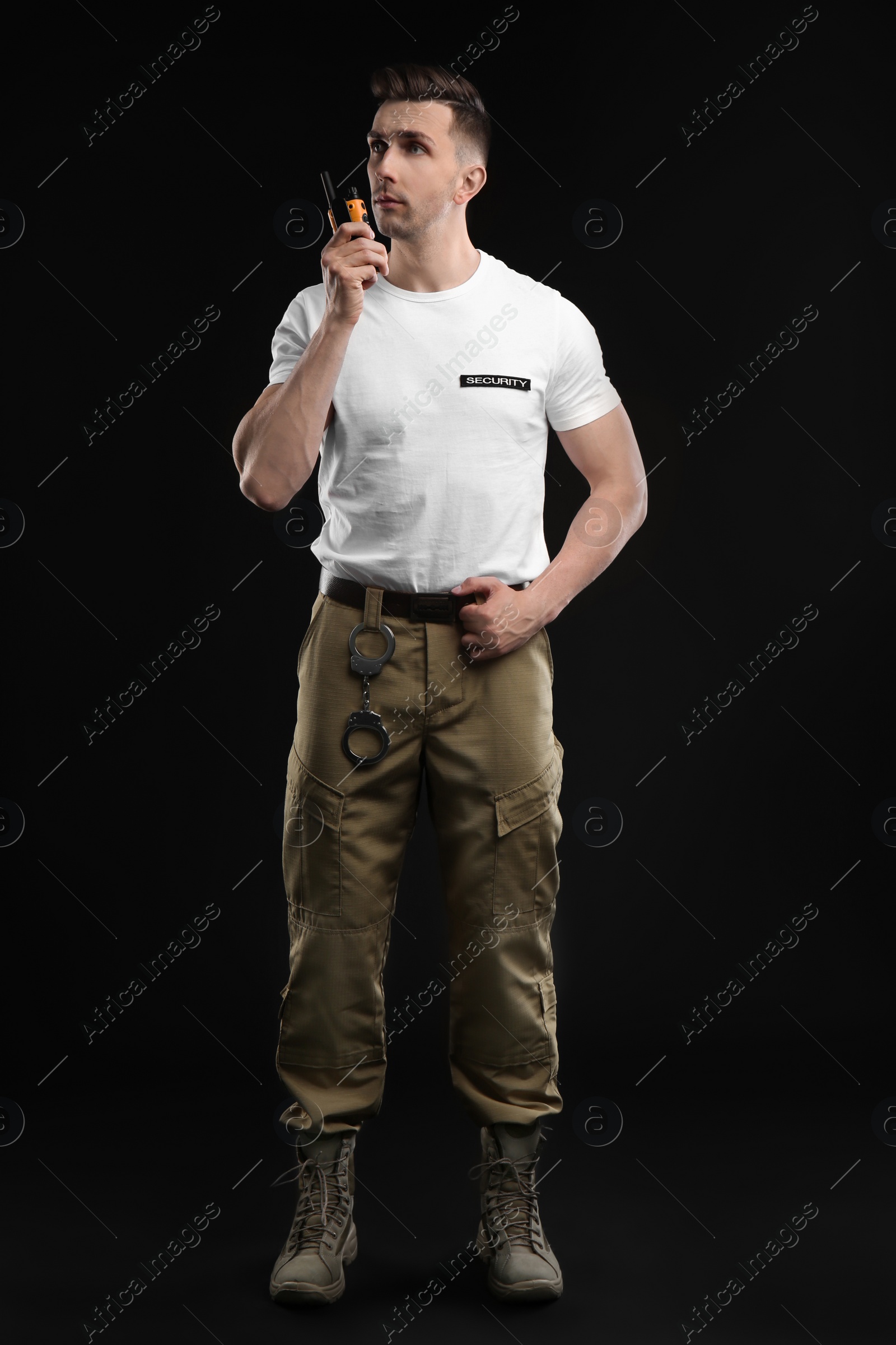 Photo of Male security guard using portable radio transmitter on dark background