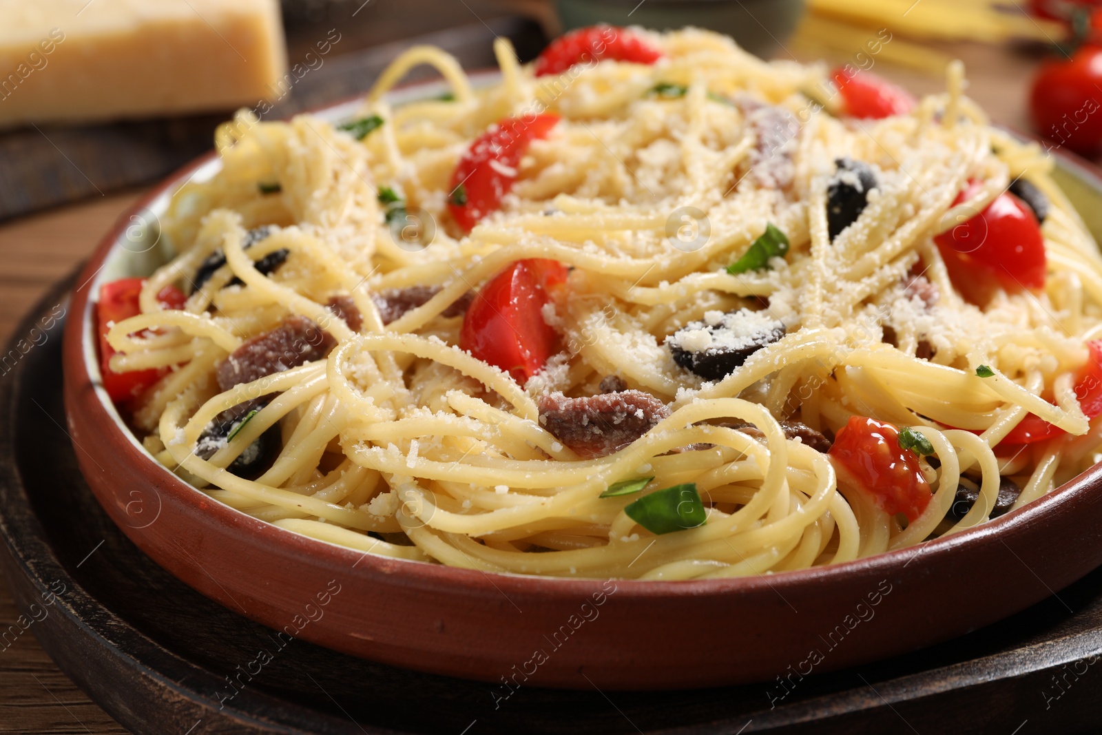 Photo of Delicious pasta with anchovies, tomatoes and parmesan cheese on table, closeup