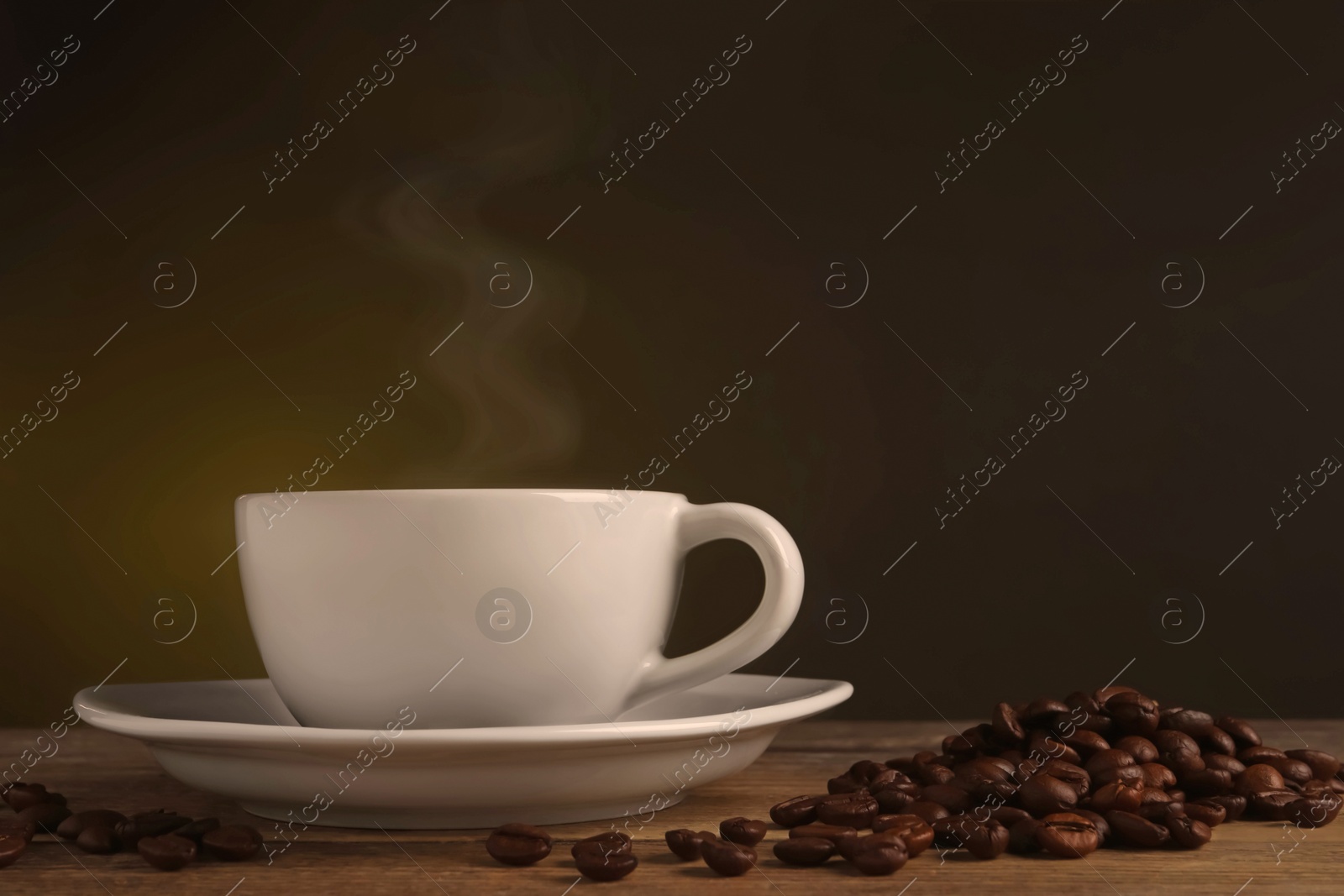 Image of Steaming coffee in cup and roasted beans on wooden table. Space for text