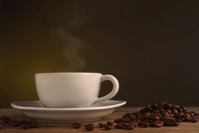 Image of Steaming coffee in cup and roasted beans on wooden table. Space for text