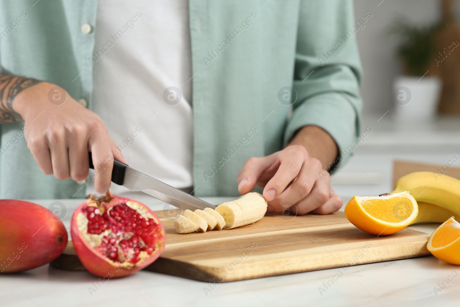 Photo of Man preparing ingredients for tasty smoothie at white marble table in kitchen, closeup