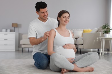 Husband massaging his pregnant wife in living room. Preparation for child birth