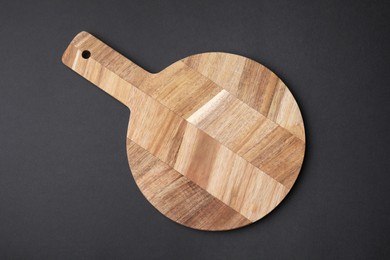 Photo of One wooden board on black background, top view