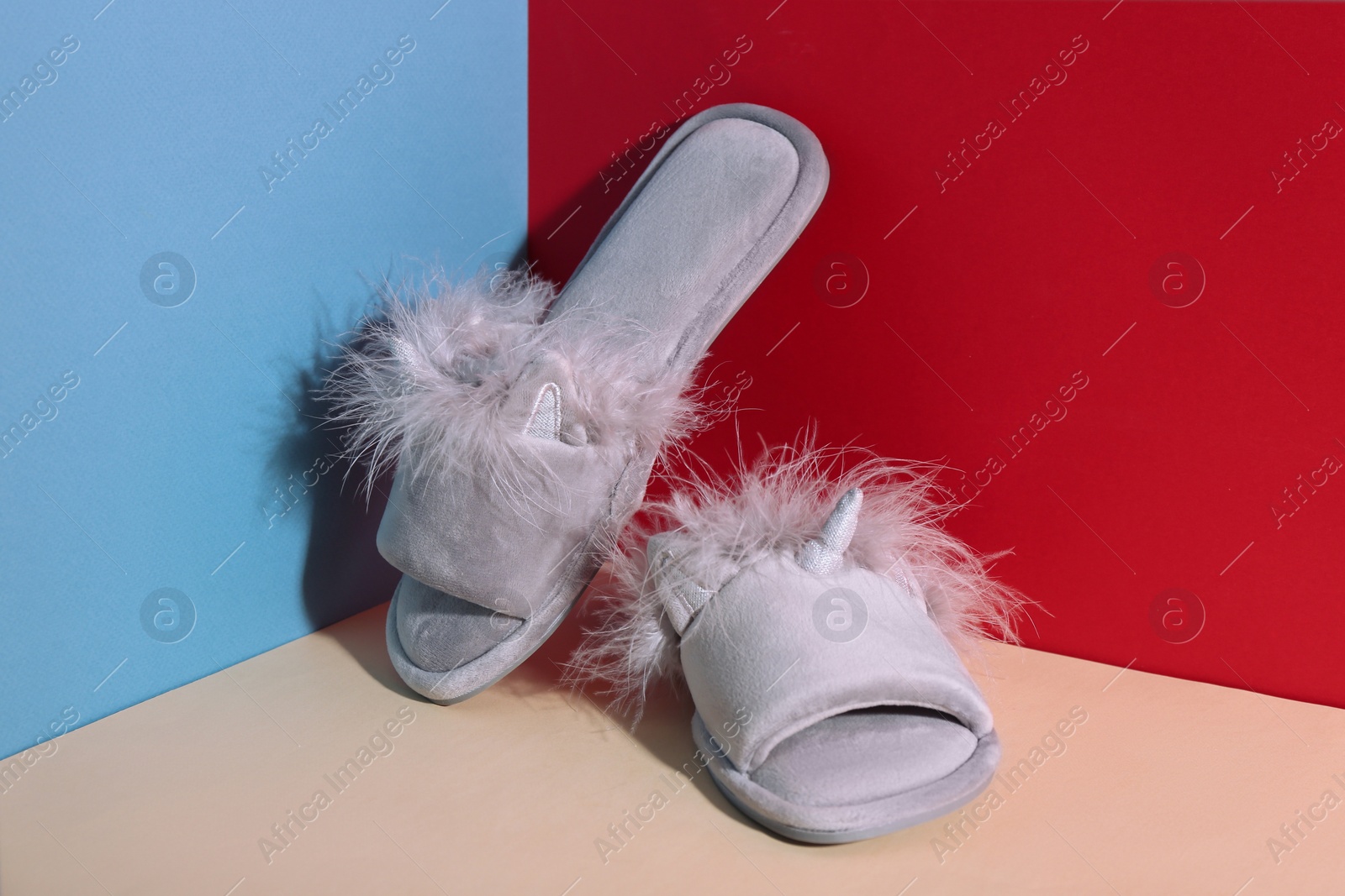 Photo of Pair of soft slippers on color background