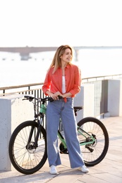 Young woman with bicycle in city on sunny day