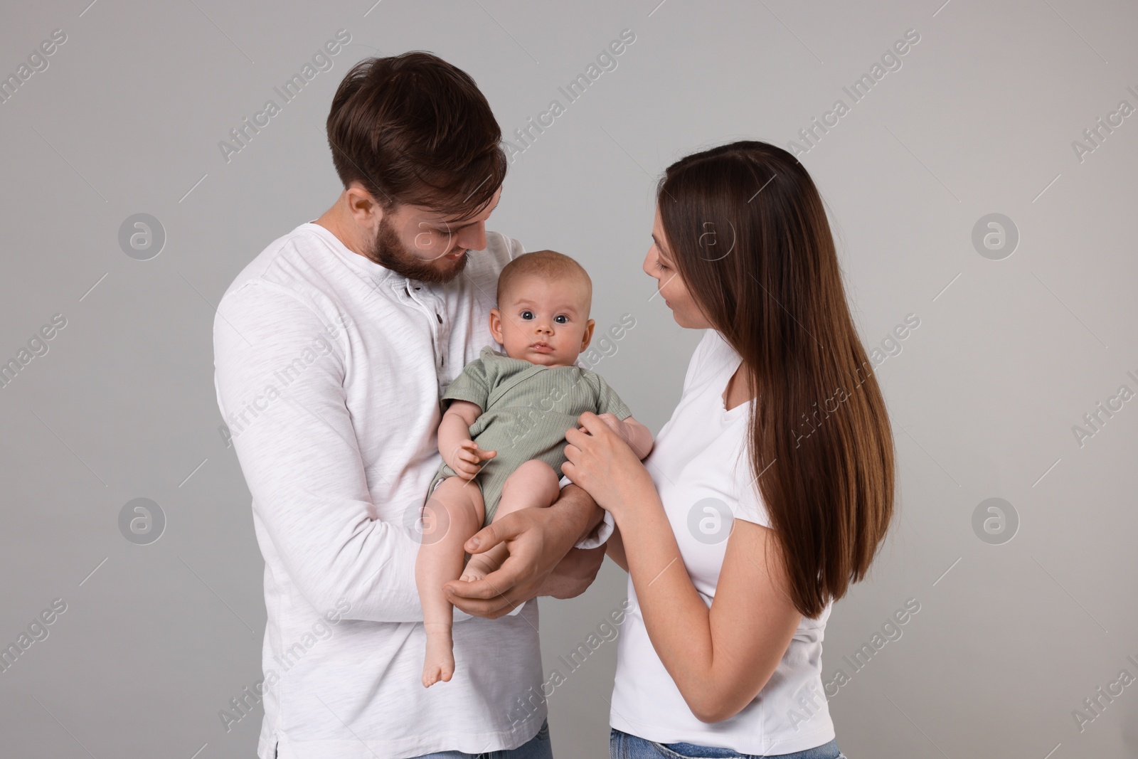 Photo of Happy family. Parents with their cute baby on grey background