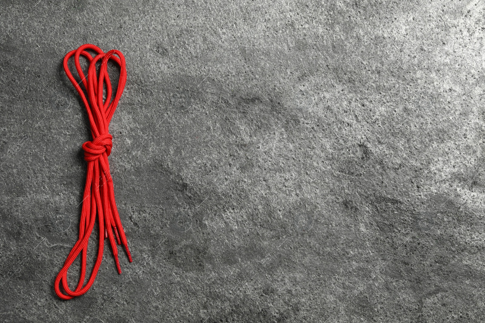 Photo of Red shoelaces on grey stone background, top view. Space for text