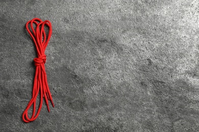 Photo of Red shoelaces on grey stone background, top view. Space for text