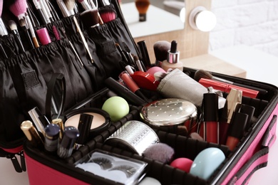 Beautician case with professional makeup products and tools on dressing table, closeup