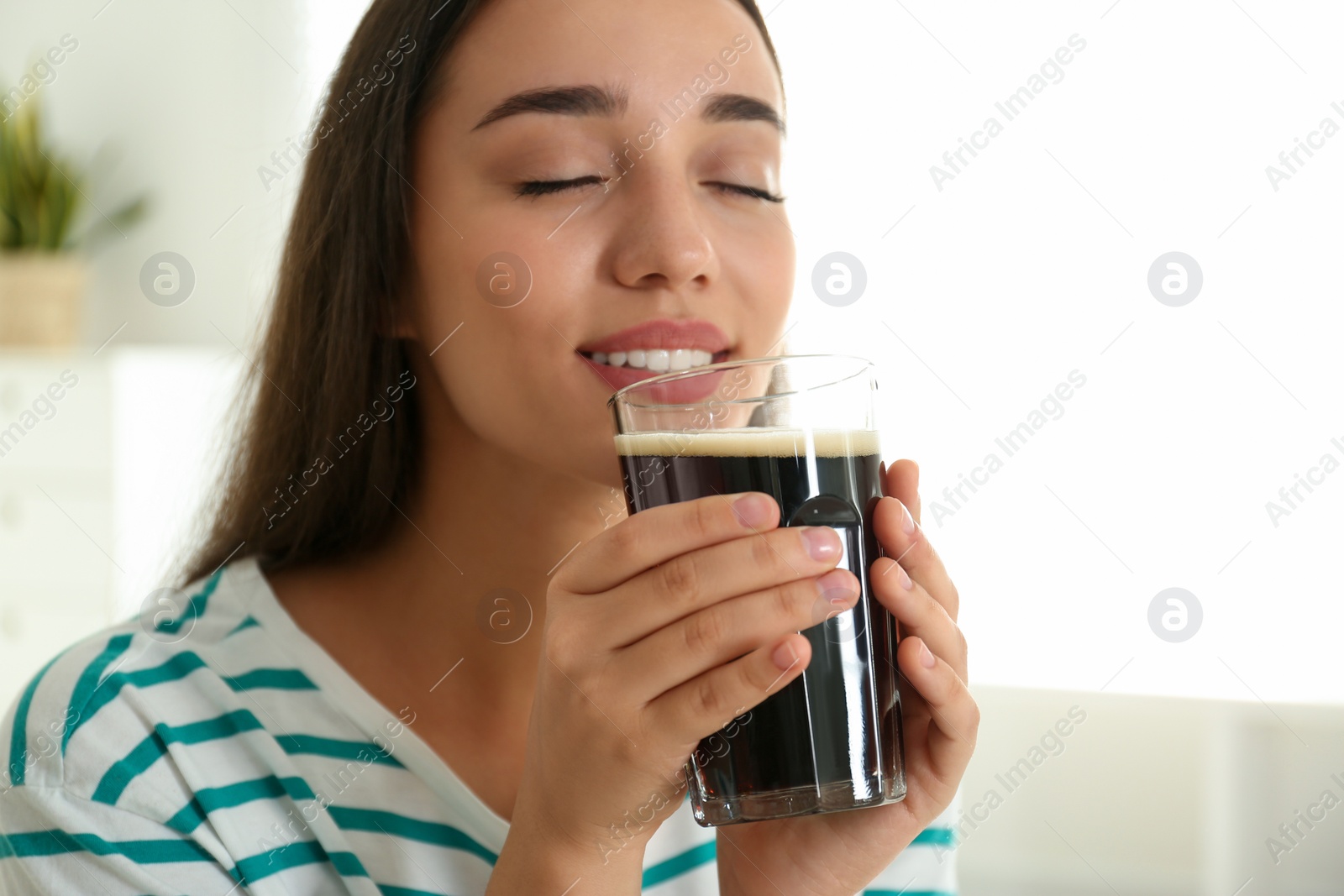 Photo of Beautiful woman with cold kvass indoors. Traditional Russian summer drink