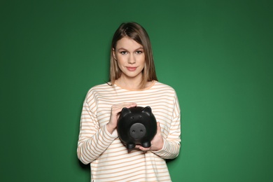 Photo of Young woman with piggy bank on color background