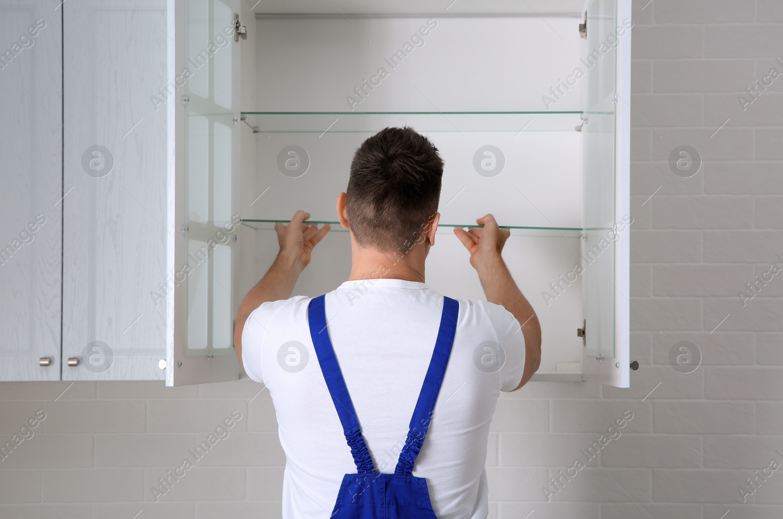 Photo of Worker installing cabinet with shelves in kitchen