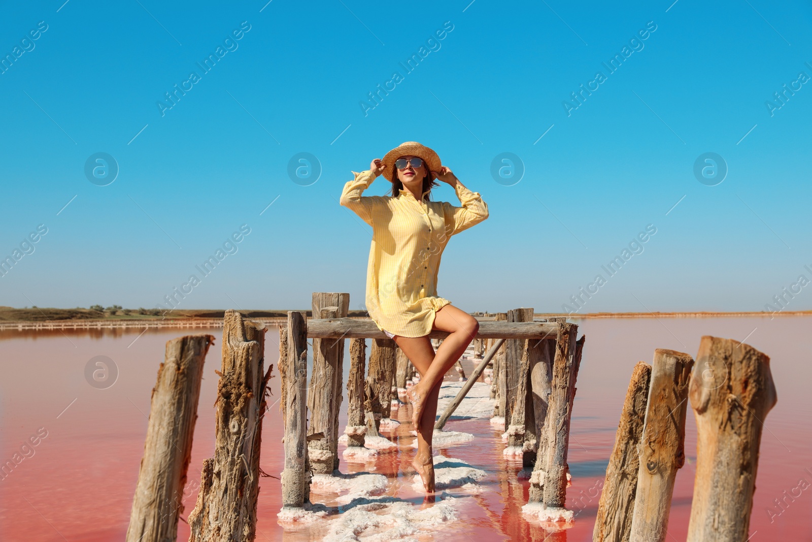 Photo of Beautiful woman with hat posing near pink lake on summer day