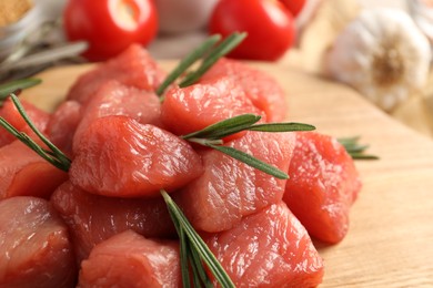 Photo of Cooking delicious goulash. Raw beef meat with rosemary on table, closeup