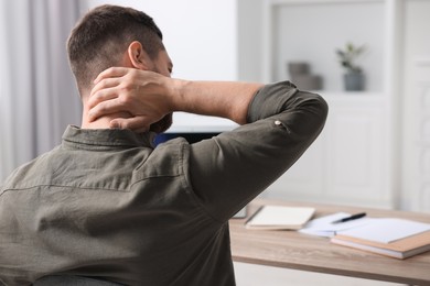 Man suffering from neck pain in office, back view