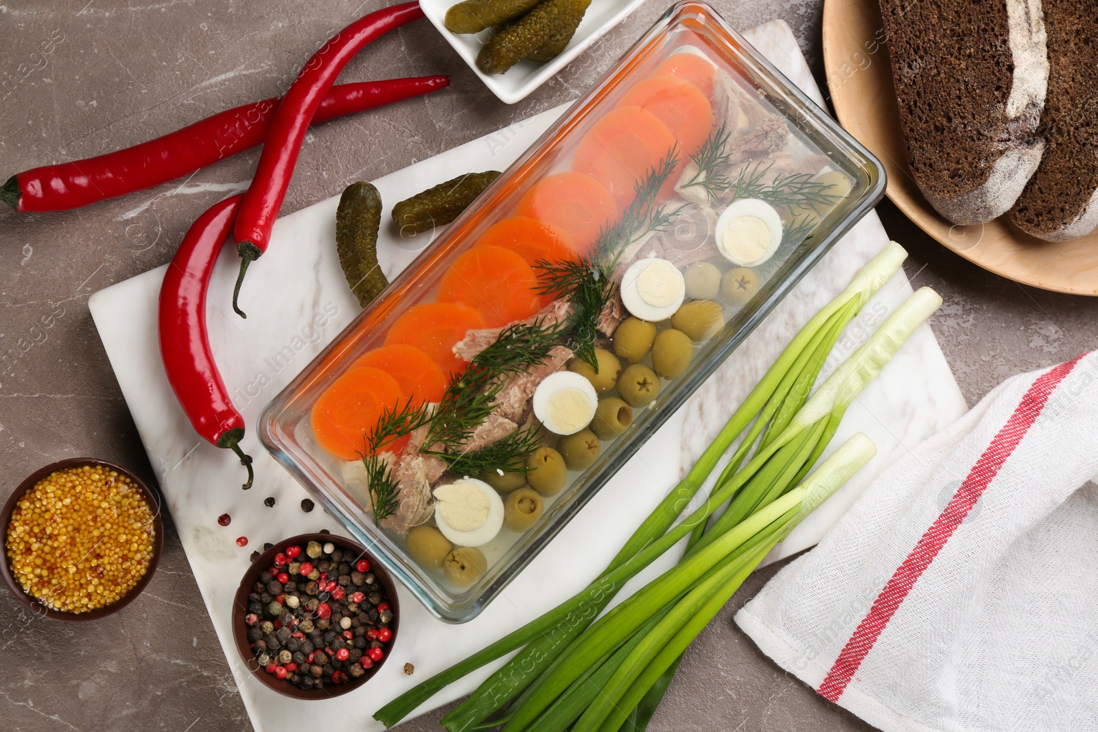 Photo of Delicious aspic with meat and vegetables served on grey table, flat lay