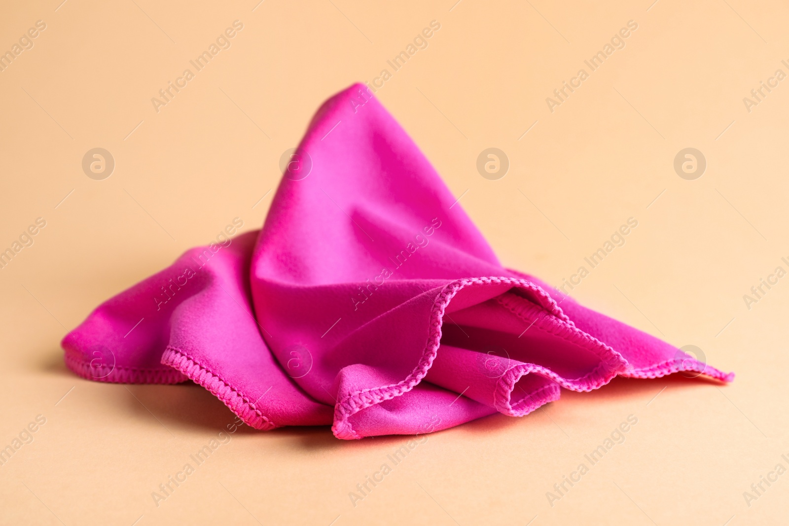 Photo of Pink microfiber cloth on beige background, closeup