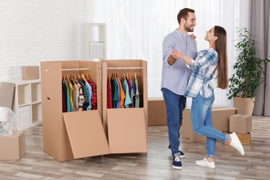 Photo of Young couple dancing near wardrobe boxes at home