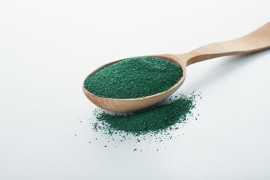 Photo of Spoon with spirulina algae powder on white background