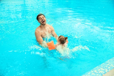 Photo of Father and daughter playing in swimming pool