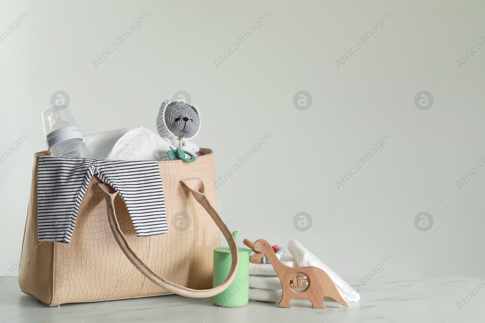 Photo of Mother's bag with baby's stuff on light grey background. Space for text