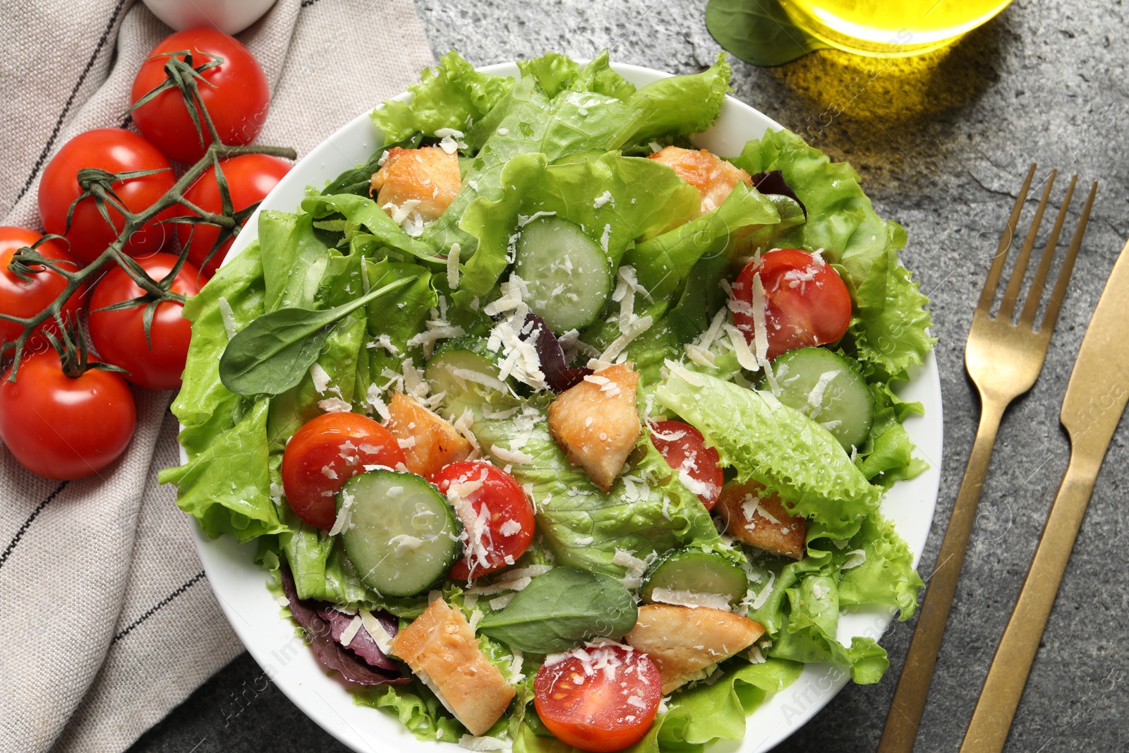 Photo of Delicious salad with chicken, cheese and vegetables served on grey table, flat lay