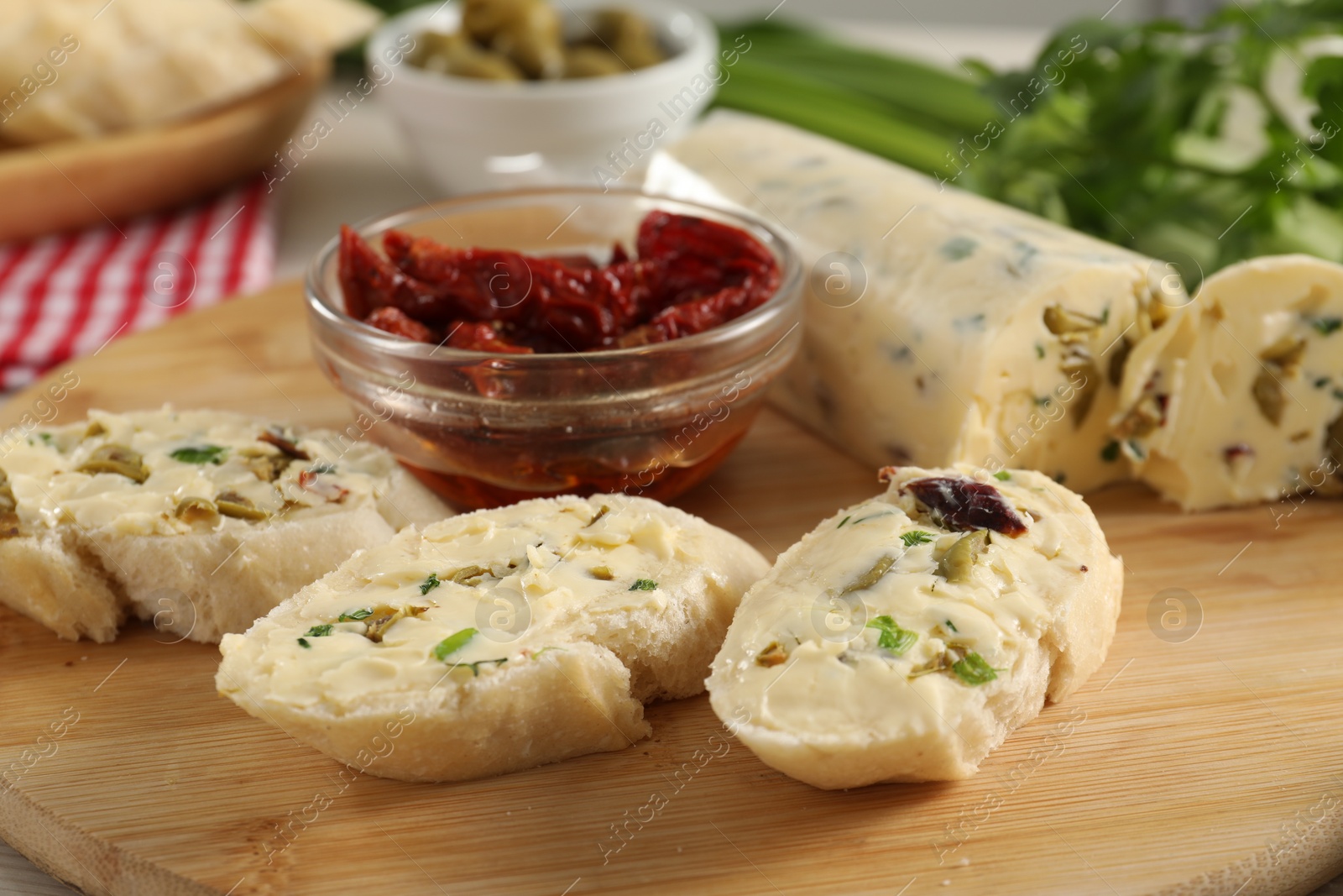 Photo of Tasty butter with olives, green onion, chili peppers and bread on table, closeup