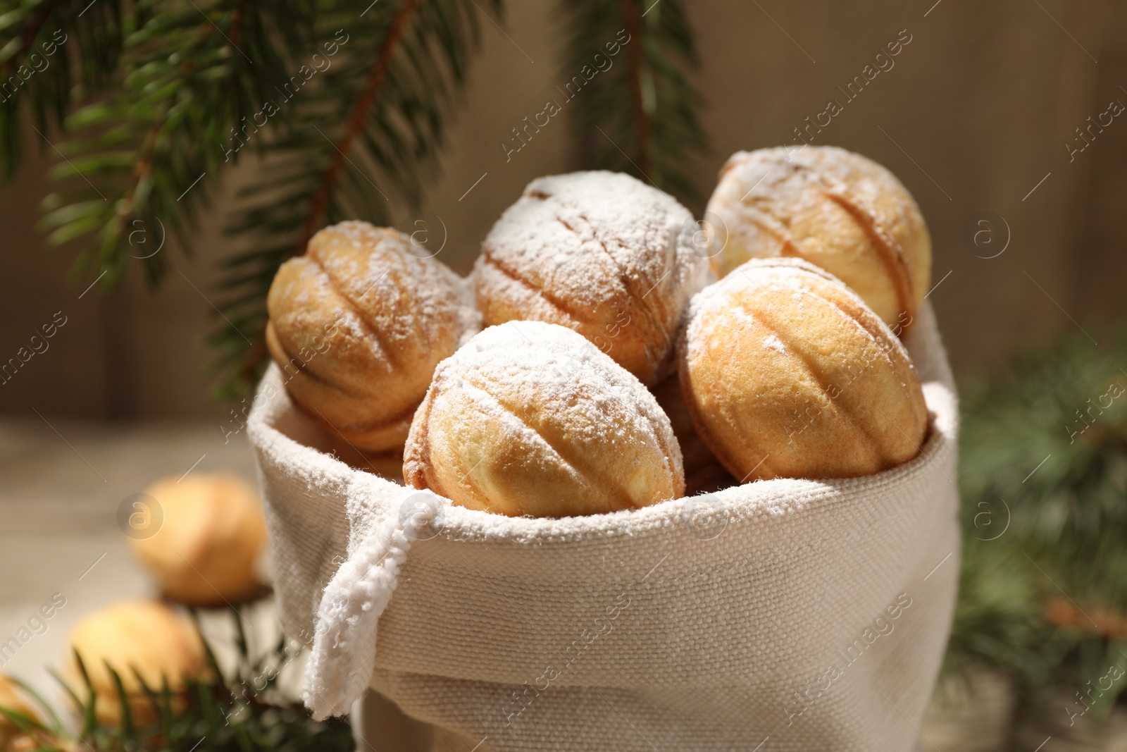 Photo of Delicious nut shaped cookies with powdered sugar in sack, closeup