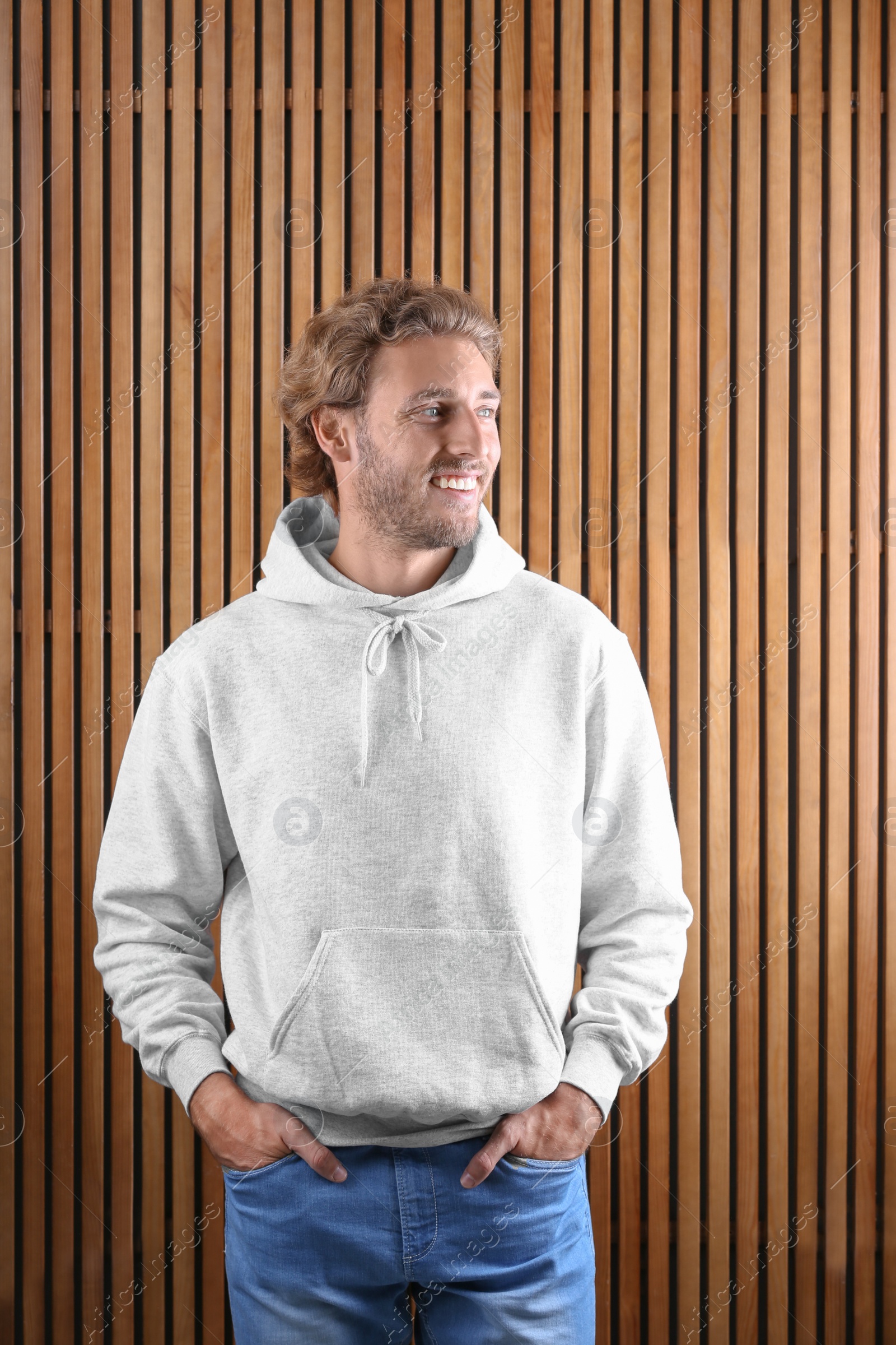 Photo of Portrait of man in hoodie sweater on wooden background. Space for design