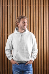 Portrait of man in hoodie sweater on wooden background. Space for design