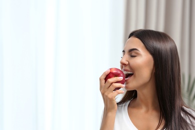 Photo of Woman eating red apple indoors. Space for text