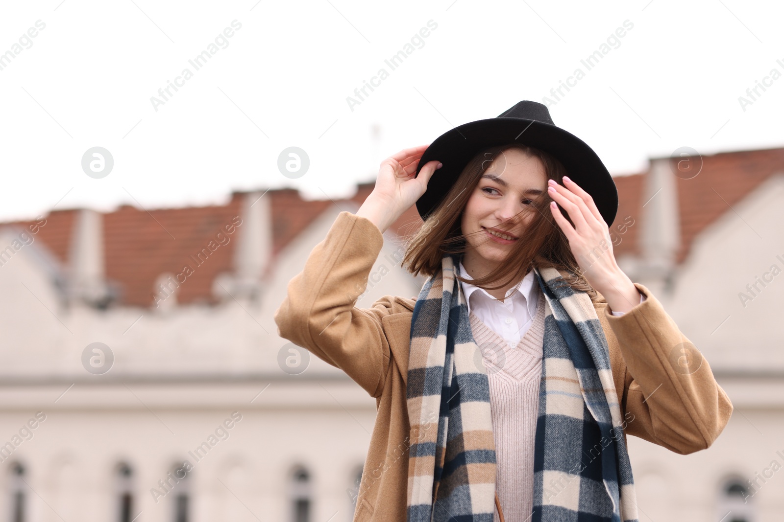 Photo of Beautiful woman in warm scarf and hat outdoors, space for text