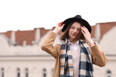 Beautiful woman in warm scarf and hat outdoors, space for text