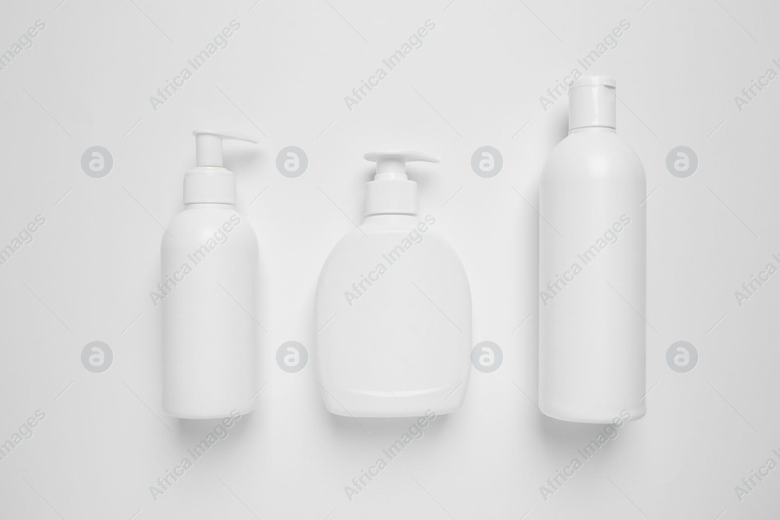 Photo of Bottles with different cosmetic products on white background, flat lay