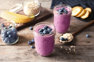 Jars with blueberry smoothies on wooden table