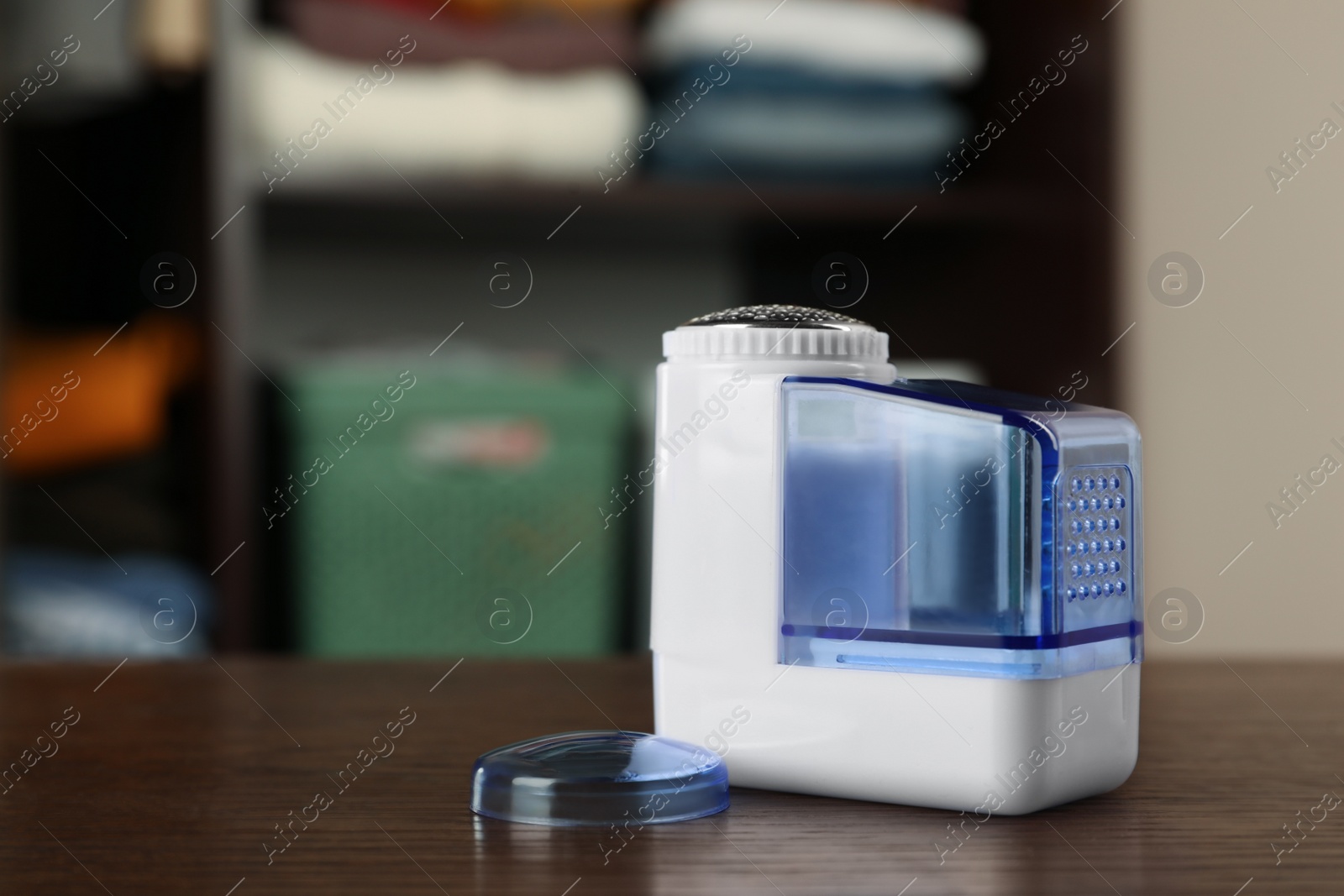 Photo of Modern fabric shaver on wooden table indoors, space for text