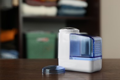 Photo of Modern fabric shaver on wooden table indoors, space for text