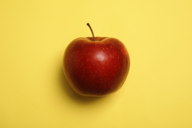 Ripe juicy red apple on yellow background, top view