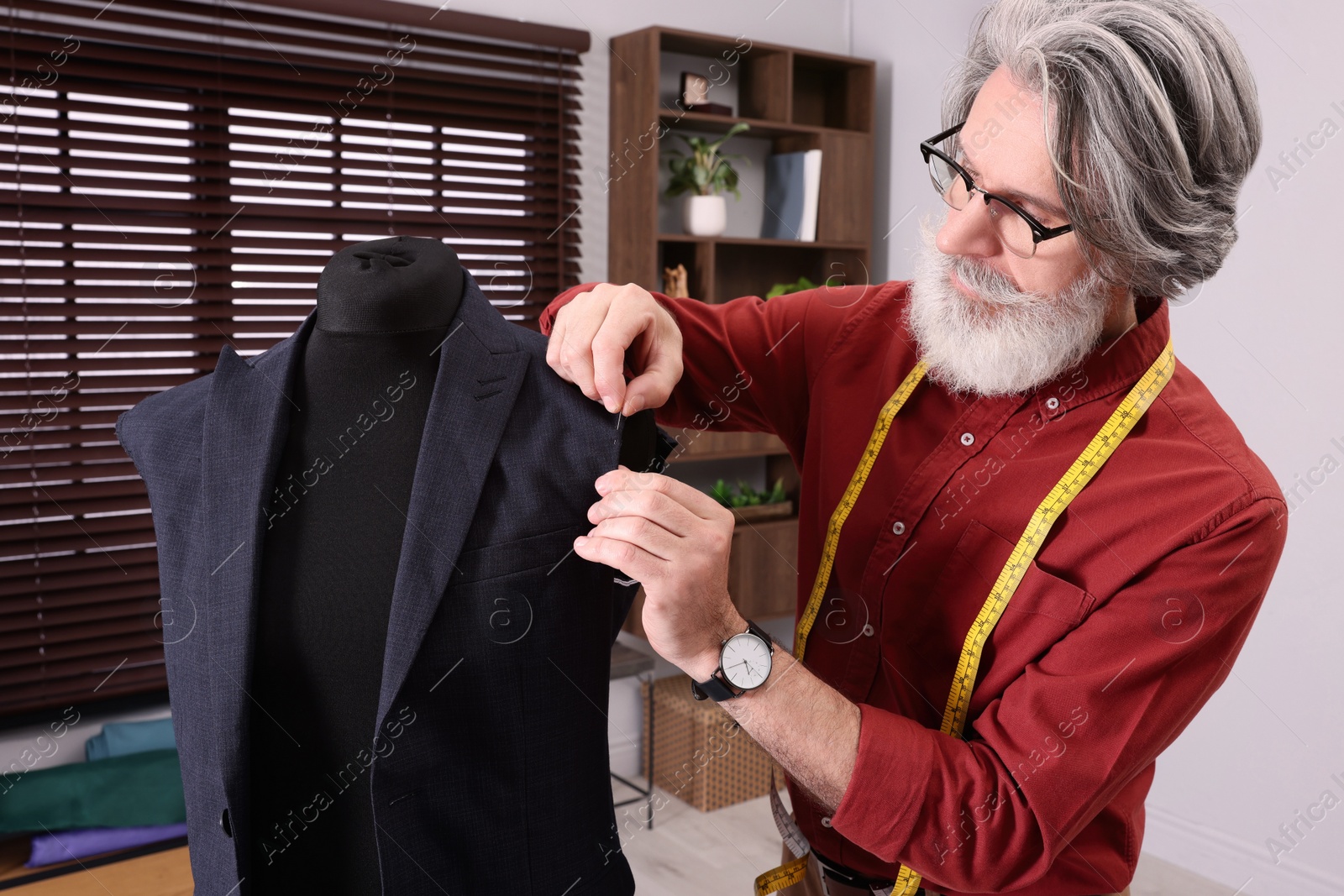 Photo of Professional tailor working with mannequin in atelier