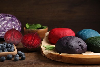 Photo of Dough painted with natural food colorings and ingredients on wooden table