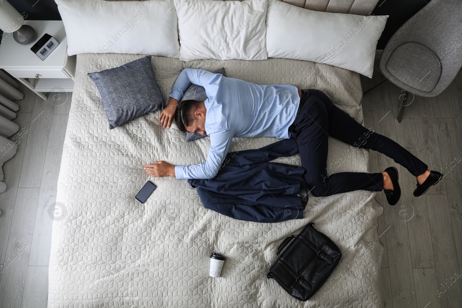 Photo of Exhausted businessman in office wear sleeping on bed at home after work, above view