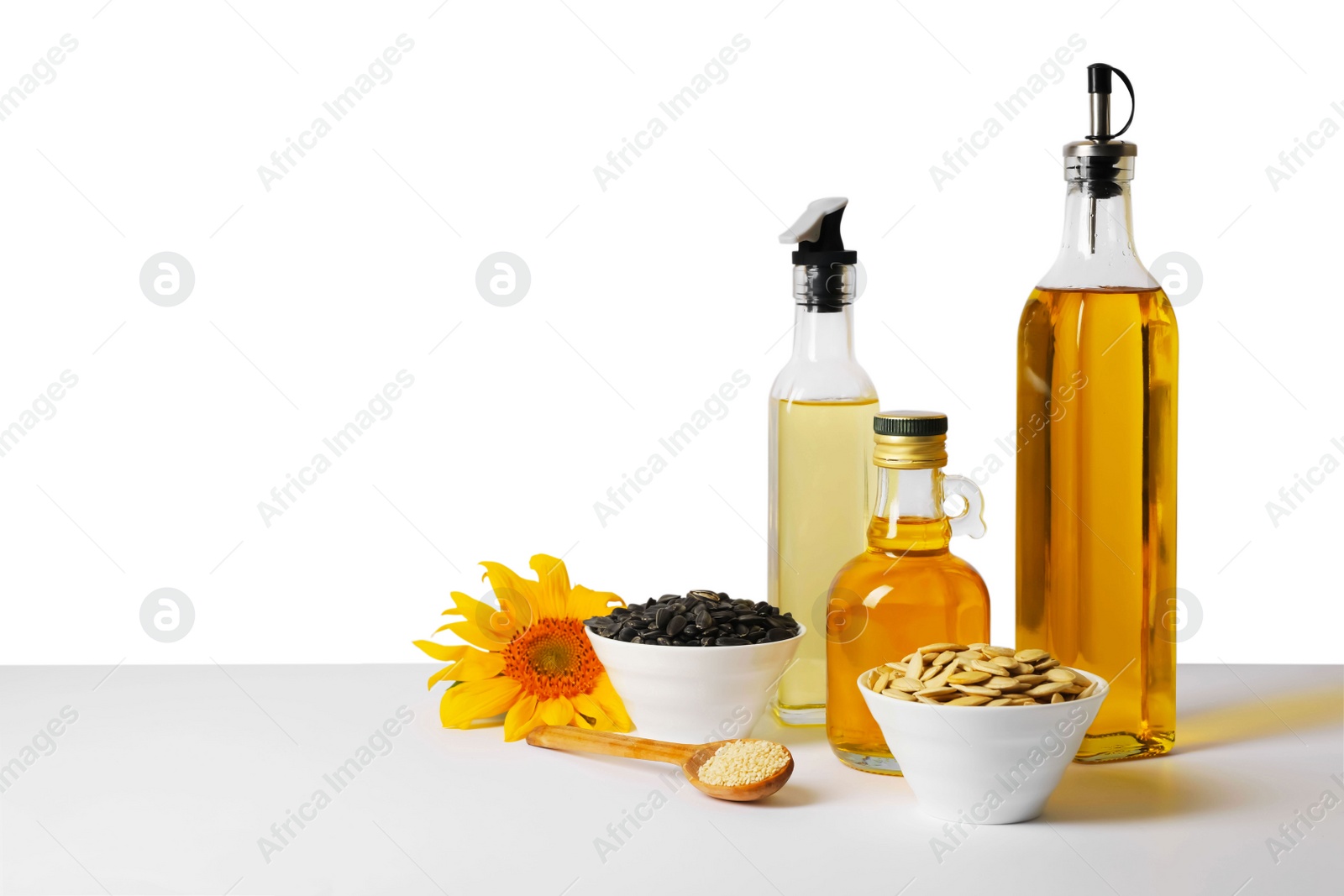 Photo of Bottles of different cooking oils, sunflower and seeds on white background