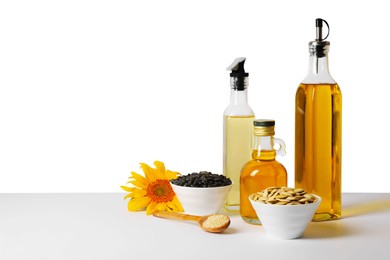 Bottles of different cooking oils, sunflower and seeds on white background