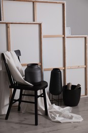 Photo of Chair with white fabric and vase near paintings in artist's studio